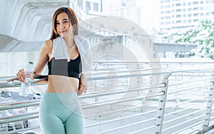 Portrait of Asian healthy and sportive beautiful woman wearing sport bra, smiling and holding water bottle, standing outside after