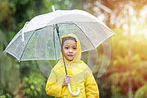 Portrait Asian kid holding an umbrella with raindrops. Happy Asian little child boy having fun playing with the rain in the