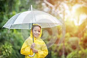 Portrait Asian kid holding an umbrella with raindrops. Happy Asian little child boy having fun playing with the rain in the