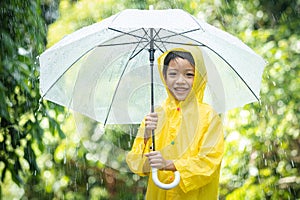 Portrait Asian kid holding an umbrella with raindrops. Happy Asian little child boy having fun playing with the rain in the