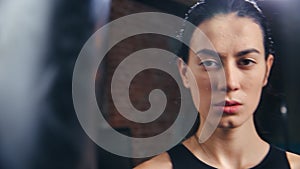 Portrait of Asian lady mma fighter with drops of sweat on skin posing at dark gym