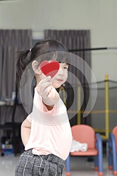 Portrait of Asian little baby girl giving red heart sign for you Focus at red heart in hands.