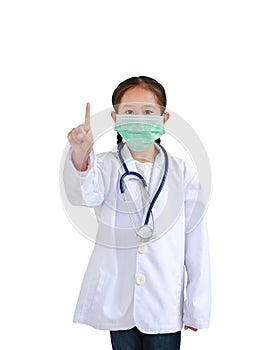 Portrait asian little child girl in doctor`s uniform with stethoscope and wearing medical mask showing one forefinger isolated on