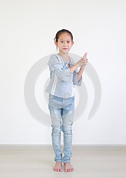 Portrait asian little child girl expression finger with imaginary gun standing in the room. Kid gesture hand in shape of gun with