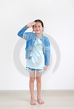 Portrait of asian little child girl saluting with hand at forehead indoor. Full-length