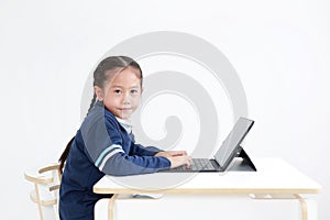Portrait asian little child girl in school uniform using laptop on table isolated on white background with looking camera, Studio