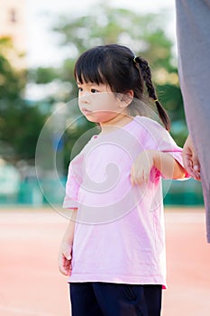Portrait Asian little child girl takes light exercise near his mother. A shy cute kid wearing a pink shirt.