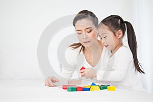 Portrait of asian little cute girl playing colorful blocks with her mother over white background.