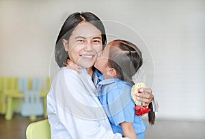 Portrait of Asian little girl kissing her happy mom and hugging on Mother`s day in thailand.