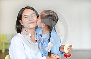 Portrait of Asian little girl kissing her happy mom and hugging on Mother`s day in thailand. Kid Pay respect.