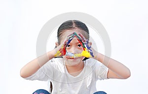 Portrait of Asian little girl looking through her colorful hands painted isolated on white background. Focus at child face. Kid