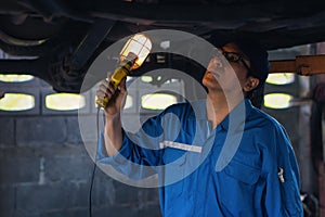 Portrait of asian male car mechanic performing car checking and maintenace service at garage and car maintenance service station