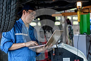 Portrait of asian male car mechanic performing car checking and maintenace service at garage and car maintenance service station
