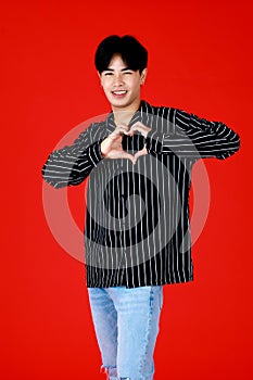 Portrait asian man about 20-25 years old standing while his hands make to heart symbol with looking at camera feel happy and smile