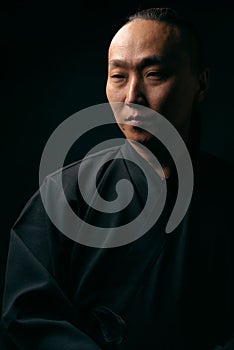 Portrait of an Asian man in a black robe on a black background