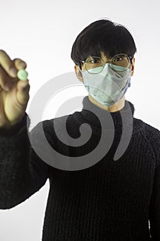 Portrait asian man in glasses, medical mask against covid-19 with pill in hand