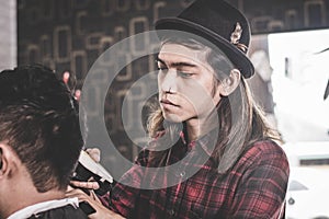 Portrait of Asian man with long brown hair work as barber with costumer