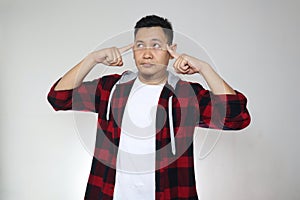 Portrait of Asian man touching his forehead with pointing finger, looking up and thinking hard, trying to remember