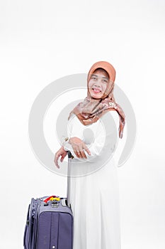 Portrait of asian mature muslim woman wear white clothes bring travel suitcase from behind