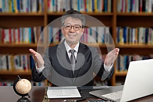 A portrait of an Asian middle-aged male businessman sitting at a desk