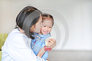 Portrait of Asian mom kissing and hugging her daughter on Mother`s day in thailand. Little child girl Pay respect.