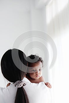 Portrait of asian mother and her black mixed race baby girl in white room