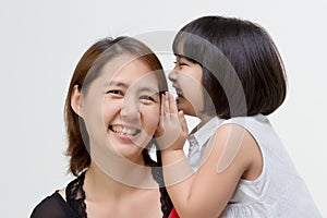 Portrait of Asian mother whispering to her daughter