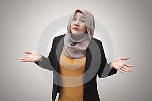 Portrait of Asian muslim businesswoman wearing hijab shows refusal or denial gesture, shoulder shrug