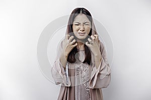 A portrait of an Asian Muslim woman wearing a headscarf isolated by white background looks depressed