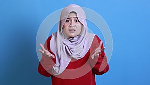 Portrait of Asian muslim woman wearing hijab shows refusal or denial gesture, shoulder shrug, I don`t know expression