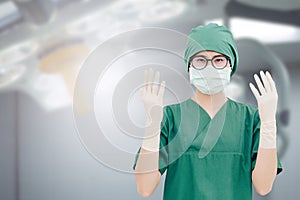 Portrait of Asian nurse raised her hands with gloves in hospital operation room.