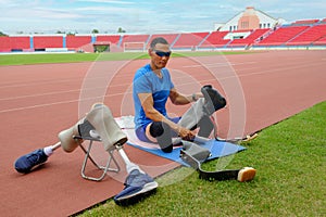 portrait of an Asian paralympic athlete, seated on a stadium track, busily affixing his running blades, preparing for intense photo