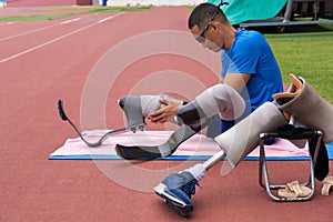 portrait of an Asian paralympic athlete, seated on a stadium track, busily affixing his running blades, preparing for intense photo