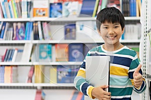 Portrait of Asian school boy in casual shirt with laptop computer in Public Library, Schooling and Learning by Computer Concept