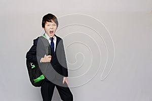 Portrait of an Asian screaming schoolboy with a schoolbag