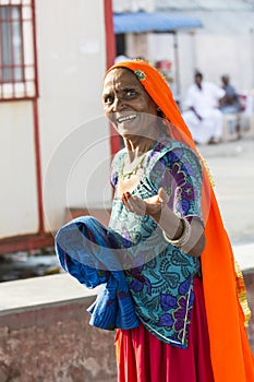 Portrait of Asian senior beautiful woman smiling wearing traditional orange and blue Indian dress sari.