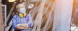 Portrait Asian senior man carpenter crossed hands wear protective mask dust and headphone.