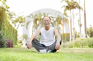 Portrait of Asian senior man relaxing and sitting on grass at th