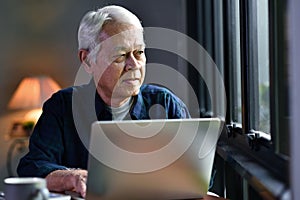 Portrait of Asian senior man using laptop computer and looking out