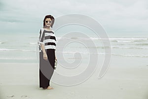 Portrait asian single hipster indy women wear sunglasses lonely stand alone on the beach