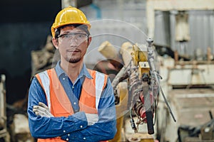Portrait Asian smart engineer male worker standing armcrossed in heavy metal factory happy smile