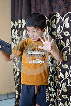 Portrait of Asian smart happy little boy using Mobile phone at home. Little boy holding mobile smart phone, online back to school