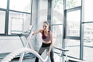 portrait of asian sportswoman working out with battle ropes