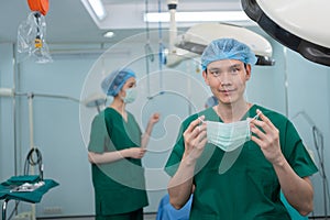 Portrait of Asian surgeon with medical mask standing in operation theater at a hospital. Team of Professional surgeons. Healthcare