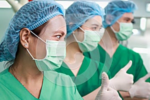 Portrait of Asian team of surgeons or doctors in green uniforms in operating room.