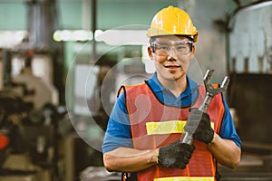 Portrait Asian technician engineer male hand holding giant wrench happy smile. heavy industry employee enjoy working.good labor