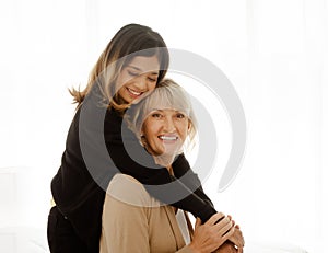 Portrait of Asian teen daughter is hugging her adopted caucasian mother