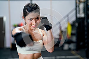 Portrait of Asian woman action of puch and hit also look at camera with smiling in fitness gym