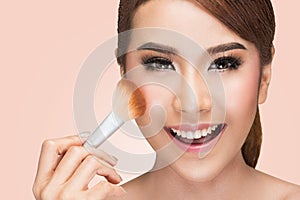 Portrait of a asian woman applying dry cosmetic tonal foundation on the face using makeup brush photo