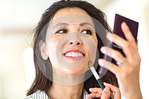 Portrait of a Asian woman applying make up.